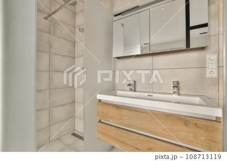 a bathroom with a sink and mirror above the counter area in front of the bathtub is white tile on the wall a bathroom with a sink and mirror above the counter area in front of the bathtub is white tile on the wall 108713119