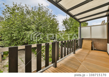 an outside area with wood flooring and wooden fenced in front of the house, surrounded by lush green trees 108715170