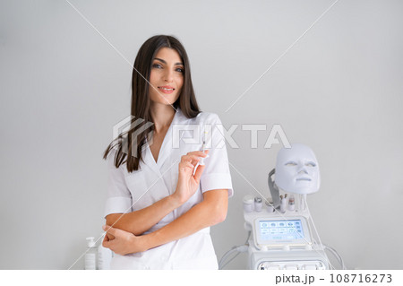 Cosmetologist standing holding syringe looking at camera 108716273