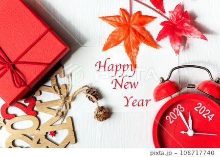 Happy New Year writing on paper note. 2023 and 2024 on red alarm clock Happy New Year writing on paper note. 2023 and 2024 on red alarm clock 108717740