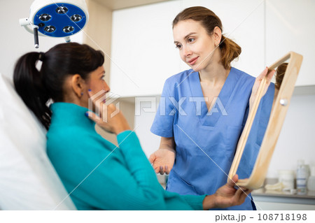 Beautician examining face skin of female patient 108718198