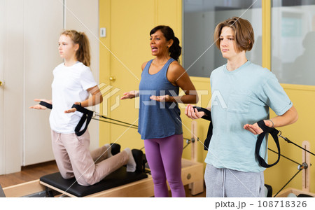 Teens doing pilates exercises with trainer 108718326