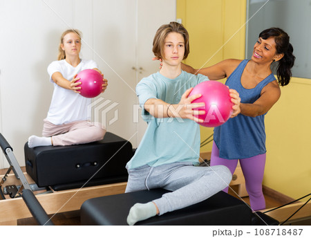 Young boy and girl with pilates trainer in gym 108718487