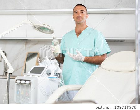 Experienced male doctor standing in clinic office with medication or collagen in hands 108718579