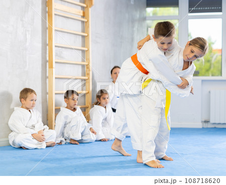 Children athletes in pair conduct training battle in oriental fighting technique Children athletes in pair conduct training battle in oriental fighting technique 108718620