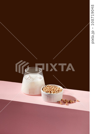 Minimal scene of a cup of fresh milk decorated with a lot of soybeans inside a white bowl. Nuts are a great source of several nutrients, including vitamin E Minimal scene of a cup of fresh milk decorated with a lot of soybeans inside a white bowl. Nuts are a great source of several nutrients, including vitamin E 108719048
