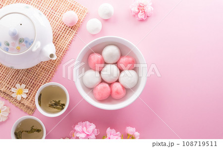 Tang Yuan(sweet dumplings balls), a traditional cuisine for Mid-autumn, Dongzhi (winter solstice ) and Chinese new year with plum flower and tea on pastel background. 108719511