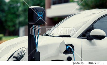 Electric car plugged in with home charging station. Peruse Electric car plugged in with home charging station. Peruse 108720085