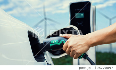 Hand insert EV charger and recharge EV car with wind turbine. Peruse 108720097