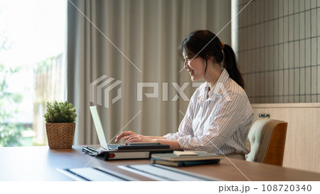 A beautiful Asian businesswoman working on her laptop at a meeting table in a meeting room alone. 108720340
