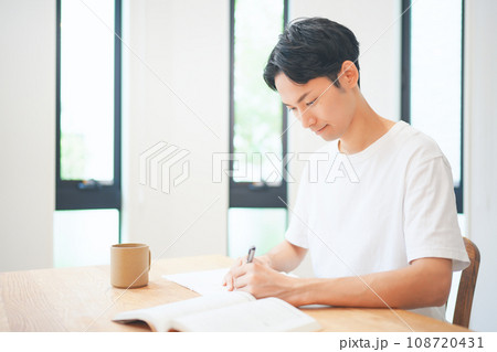 自宅のリビングで資格取得のために勉強する若い男性 自宅のリビングで資格取得のために勉強する若い男性 108720431
