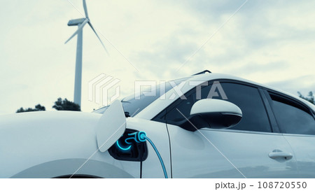 Electric car recharging energy from charging station in wind turbine farm.Peruse Electric car recharging energy from charging station in wind turbine farm.Peruse 108720550