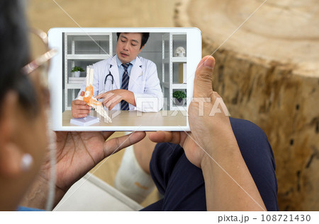 Back view of woman Telehealth consultation on the tablet screen with a male doctor with lab coat and stethoscope. 108721430