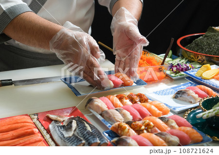 A skilled chef prepare a variety of sushi on a table. Mixing flavor, texture, and color, the chef creates culinary art. Each sushi is a precise masterpiece, showcasing their expertise and dedication. A skilled chef prepare a variety of sushi on a table. Mixing flavor, texture, and color, the chef creates culinary art. Each sushi is a precise masterpiece, showcasing their expertise and dedication. 108721624