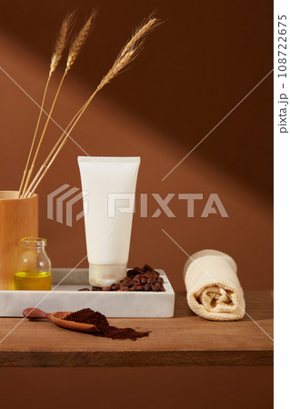 Coffee beans and coffee powder decorated with plastic tube on wooden pedestal and brown background. Vintage concept for advertising organic cosmetic. Front view, space for design 108722675