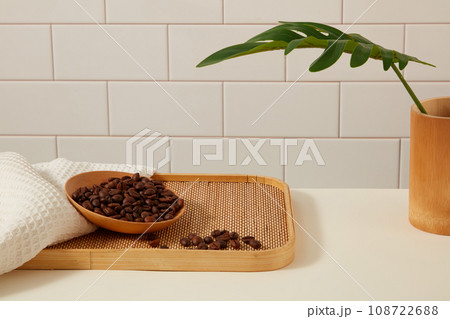 Creative background for advertising product with ingredient from coffee. Coffee beans placed on wooden dish and decorated with white towel and green leaves on ceramic tile background 108722688