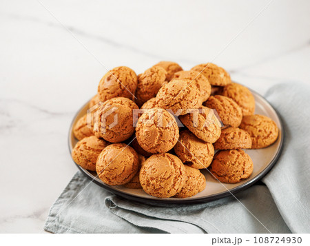 Plate of cookie amaretti on white marble background - traditional Italian Sardinian pastry. Delicious amaretti biscuit cookies made from almond or apricot kernels with copy space 108724930