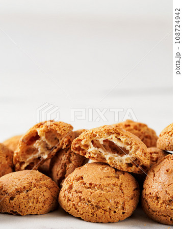 pile of cookie amaretti on white marble background - traditional Italian Sardinian pastry. Amaretti biscuit cookies made from almond or apricot kernels with copy space. Vertical pile of cookie amaretti on white marble background - traditional Italian Sardinian pastry. Amaretti biscuit cookies made from almond or apricot kernels with copy space. Vertical 108724942