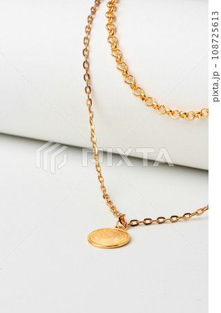 Golden chain with pendant on paper background close up Golden chain with pendant on paper background close up 108725613
