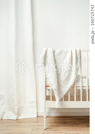 Muslin baby blanket hanging on child's bed in nursing room 108725742