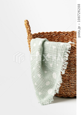 Soft cotton blanket in a straw basket on white background 108726288