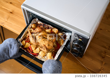焼き上がったローストチキンをオーブンから取り出す 108726345