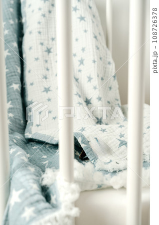 Soft blue muslin blanket hanging on a baby's bed Soft blue muslin blanket hanging on a baby's bed 108726378