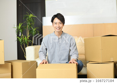大量の段ボール箱の前で片付けをする若いアジア人男性 108727184