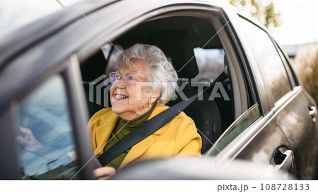 Happy senior woman driving car alone, enjoying car ride. Safe driving for elderly adults, older driver safety. Happy senior woman driving car alone, enjoying car ride. Safe driving for elderly adults, older driver safety. 108728133