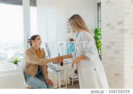 Teenage patient arriving at appointment with doctor, shaking hands with female pediatrician, physician. Teen girl have consultation, first visit with gynecologist. Concept of preventive health care 108728258