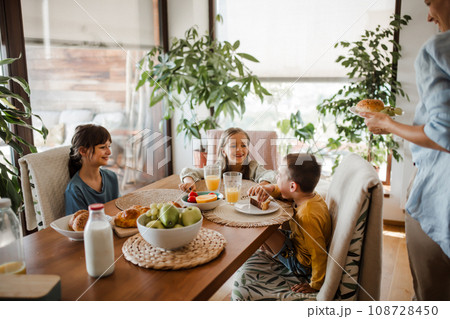 Mother prepares breakfast for children, in the morning. Maternal love and care for household and family. 108728450