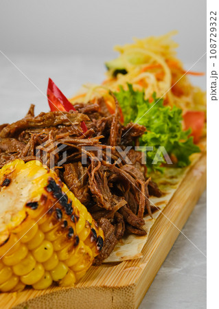 Pulled beef served with grilled corn and pickled vegetables 108729322