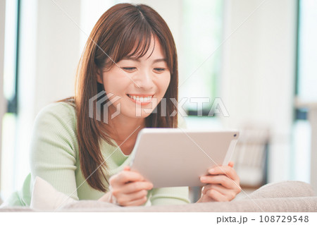 リビングでタブレットで動画を視聴する女性 108729548