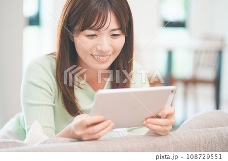 リビングでタブレットで動画を視聴する女性 リビングでタブレットで動画を視聴する女性 108729551
