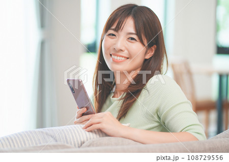 リビングでスマートフォンを操作する女性 リビングでスマートフォンを操作する女性 108729556