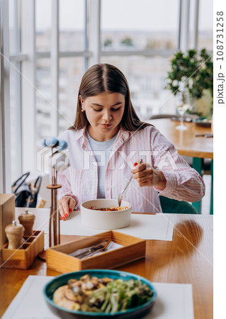 Young attractive woman enjoys tasty meal on cafe or restaurant background Young attractive woman enjoys tasty meal on cafe or restaurant background 108731258