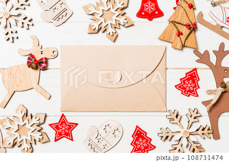 Top view of envelope on festive wooden background. Christmas toys and decorations. New Year time concept Top view of envelope on festive wooden background. Christmas toys and decorations. New Year time concept 108731474
