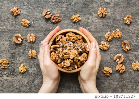 Woman hands holding a wooden bowl with walnut nuts. Healthy food and snack. Vegetarian snacks of different nuts 108731527