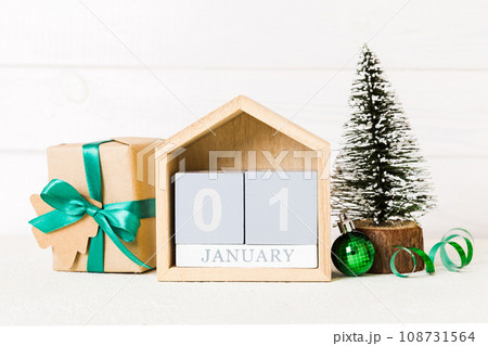 1 january. Christmas composition on colored background with a wooden calendar, with a gift box, toys, bauble copy space 108731564