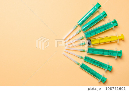 Top view of medical syringes with needles at orange background with copy space. Injection treatment concept 108731601