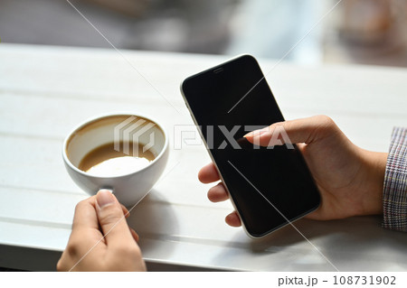 Closeup view woman hand holding cup of coffee and smartphone Closeup view woman hand holding cup of coffee and smartphone 108731902