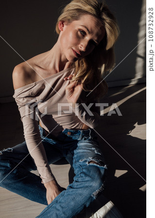 fashion woman blonde sitting in a dark room 108732928