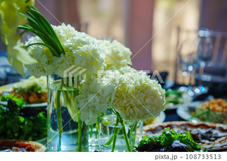 Vase with a bouquet of white flowers on the banquet table.  108733513