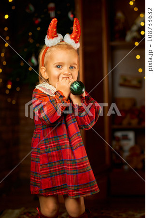 Little girl wearing Santa suit and red horns against white background 108733632