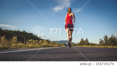 Fitness blonde woman running on the asphalt road at the mountains Fitness blonde woman running on the asphalt road at the mountains 108734270