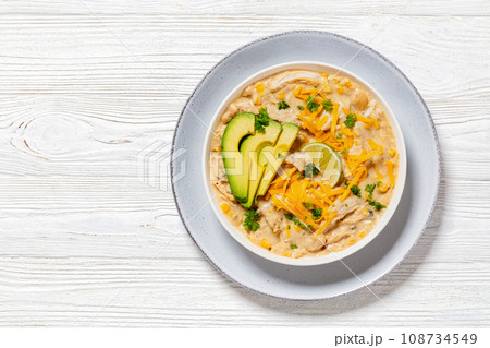 white chicken chili with cheese, avocado in bowl white chicken chili with cheese, avocado in bowl 108734549