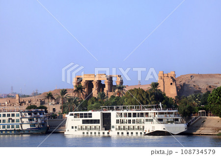 Cruise ship on Nile river near Kom Ombo Temple of gods Horus and Sobek, Egypt, Africa. Luxury Nile Cruise. Summer vacation, relaxing on cruise ship. Com-Ombo Temple in the light of sunset 108734579