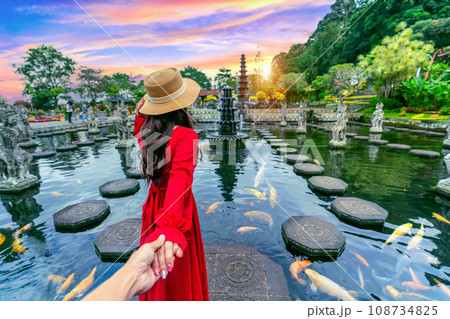 Women tourists holding man's hand and leading him to Tirta Gangga Water Palace in Bali, Indonesia. Women tourists holding man's hand and leading him to Tirta Gangga Water Palace in Bali, Indonesia. 108734825