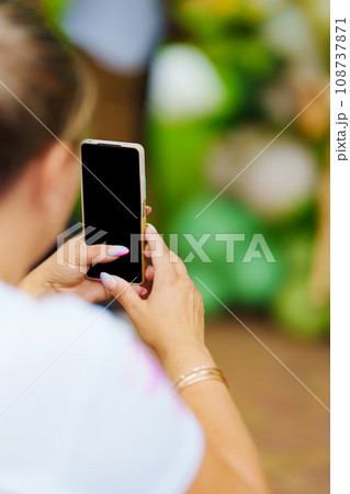 without a face. A woman takes a photo of a photo zone at a party.  108737871