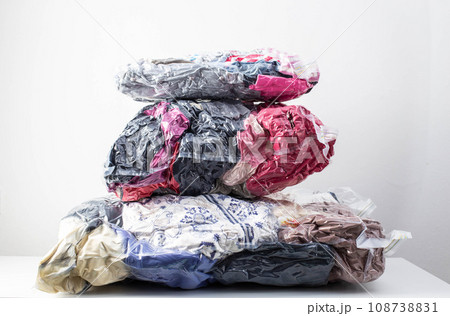 Multi-colored clothes and things packed in vacuum bags for storage on a white background. Modern compact storage technology, close-up Multi-colored clothes and things packed in vacuum bags for storage on a white background. Modern compact storage technology, close-up 108738831